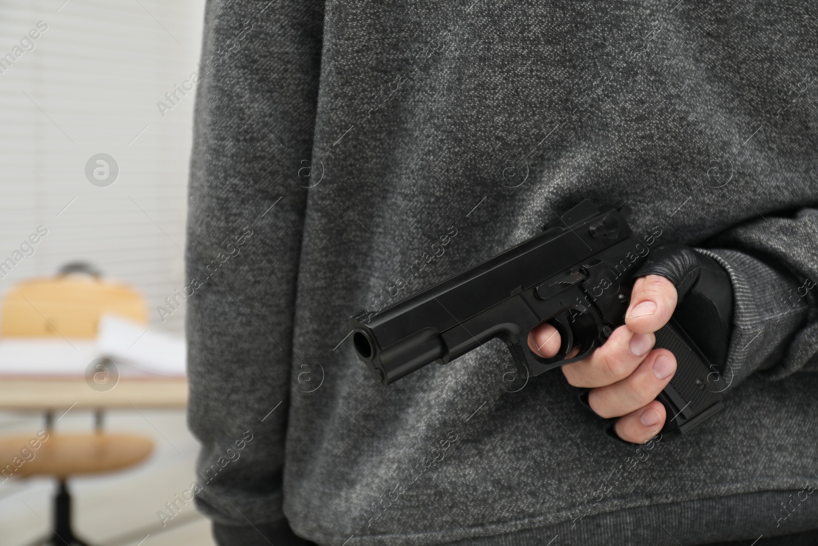 Photo of Man hiding gun behind his back indoors, closeup. Armed robbery