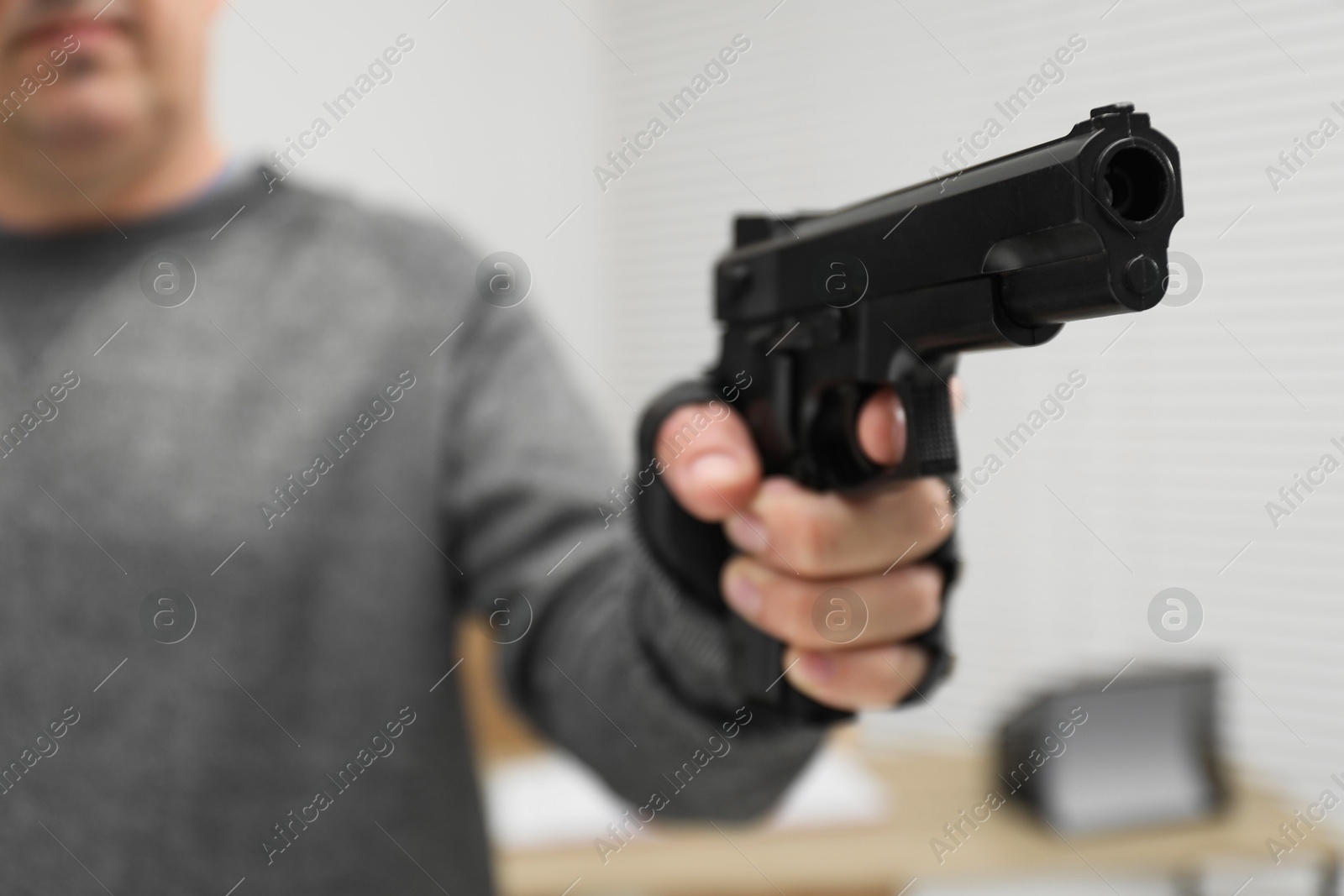 Photo of Dangerous criminal with gun indoors, selective focus. Armed robbery