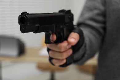 Photo of Dangerous criminal with gun indoors, closeup. Armed robbery