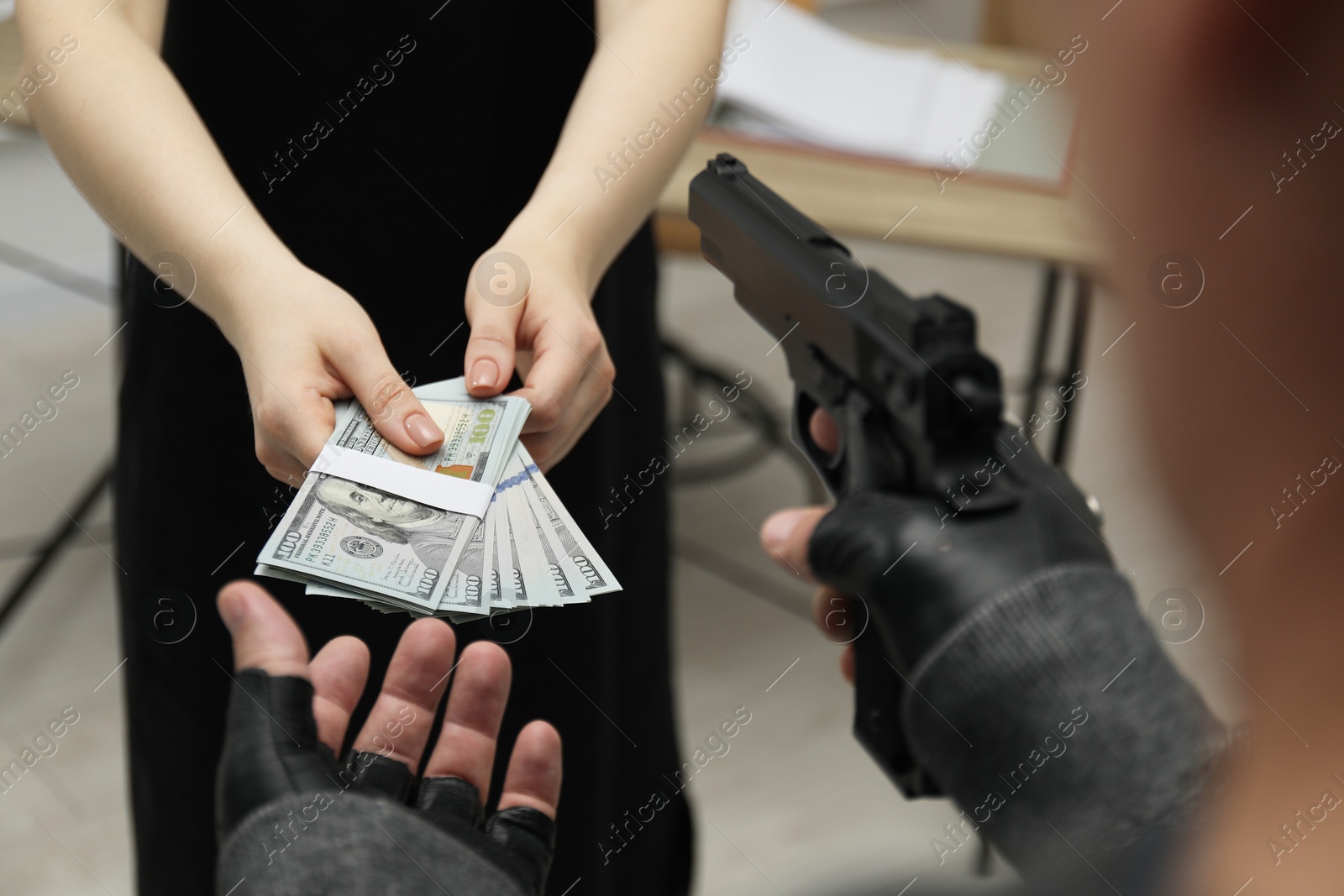 Photo of Woman giving money to criminal with gun indoors, closeup. Armed robbery