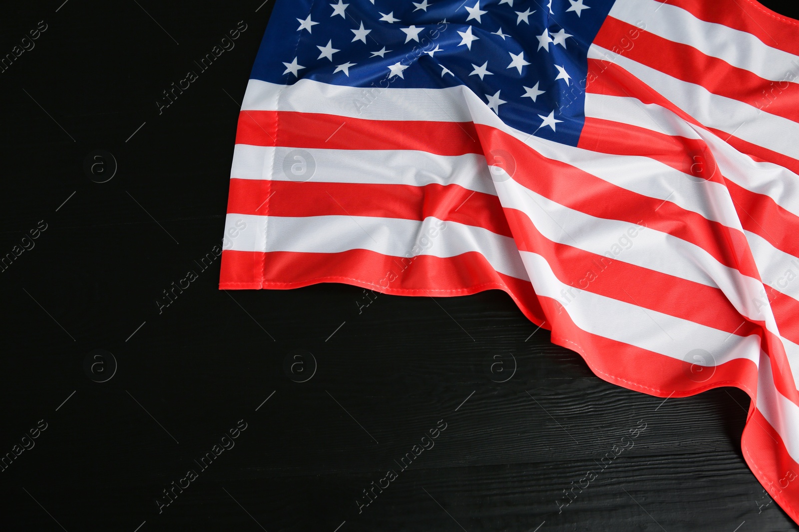 Photo of Flag of USA on black wooden table, top view. Space for text