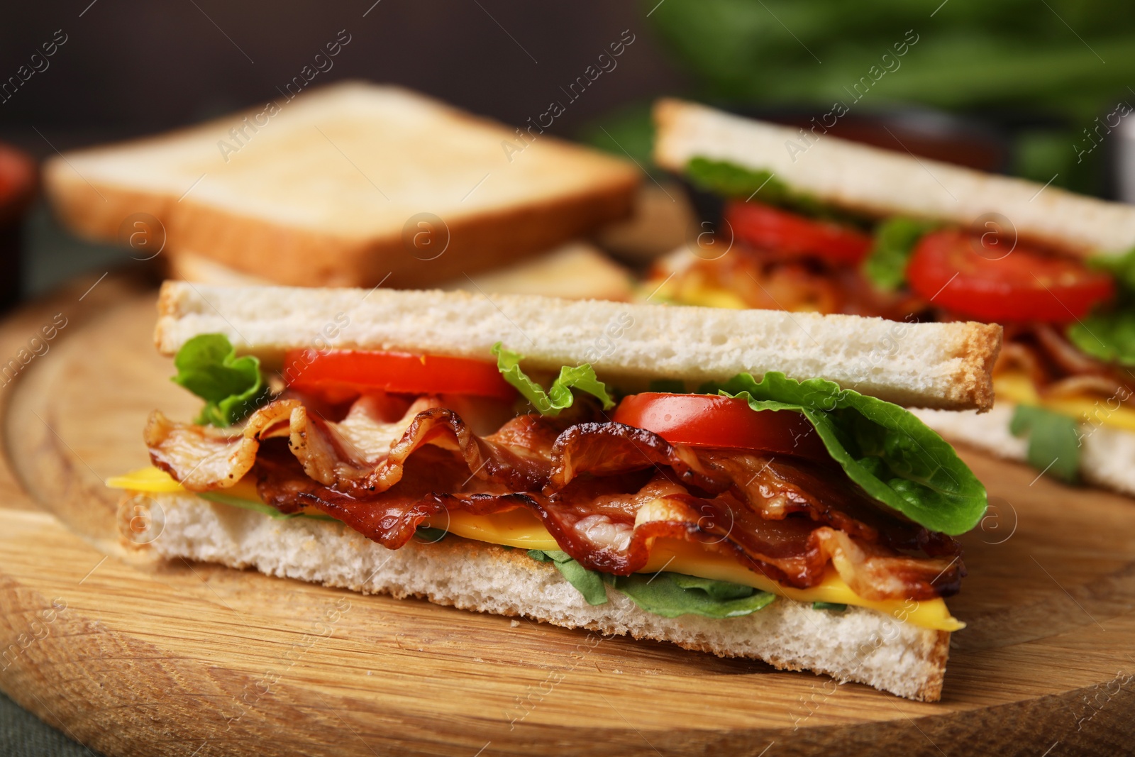 Photo of Delicious sandwich with fried bacon on wooden board, closeup