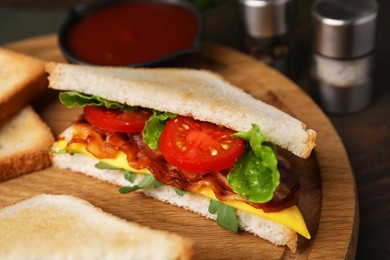 Delicious sandwich with fried bacon on wooden board, closeup