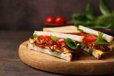 Photo of Delicious sandwiches with fried bacon on wooden table, closeup