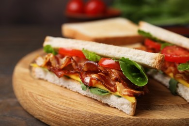 Photo of Delicious sandwiches with fried bacon on wooden table, closeup