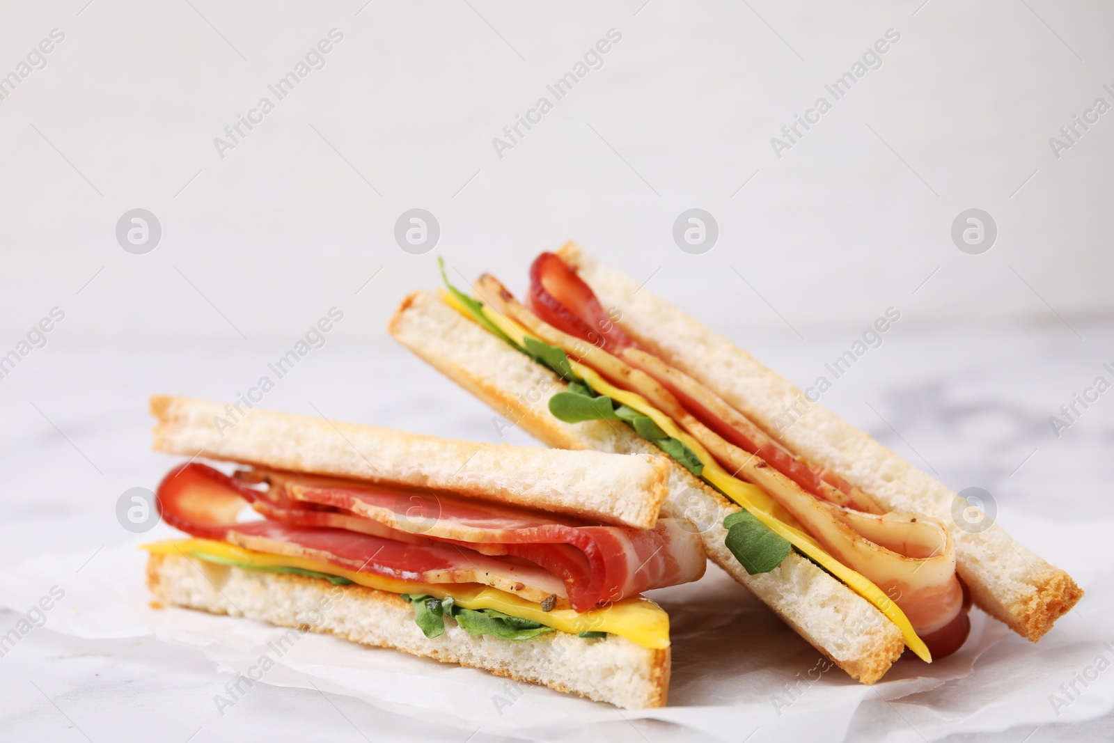 Photo of Delicious sandwiches with bacon on white table, closeup