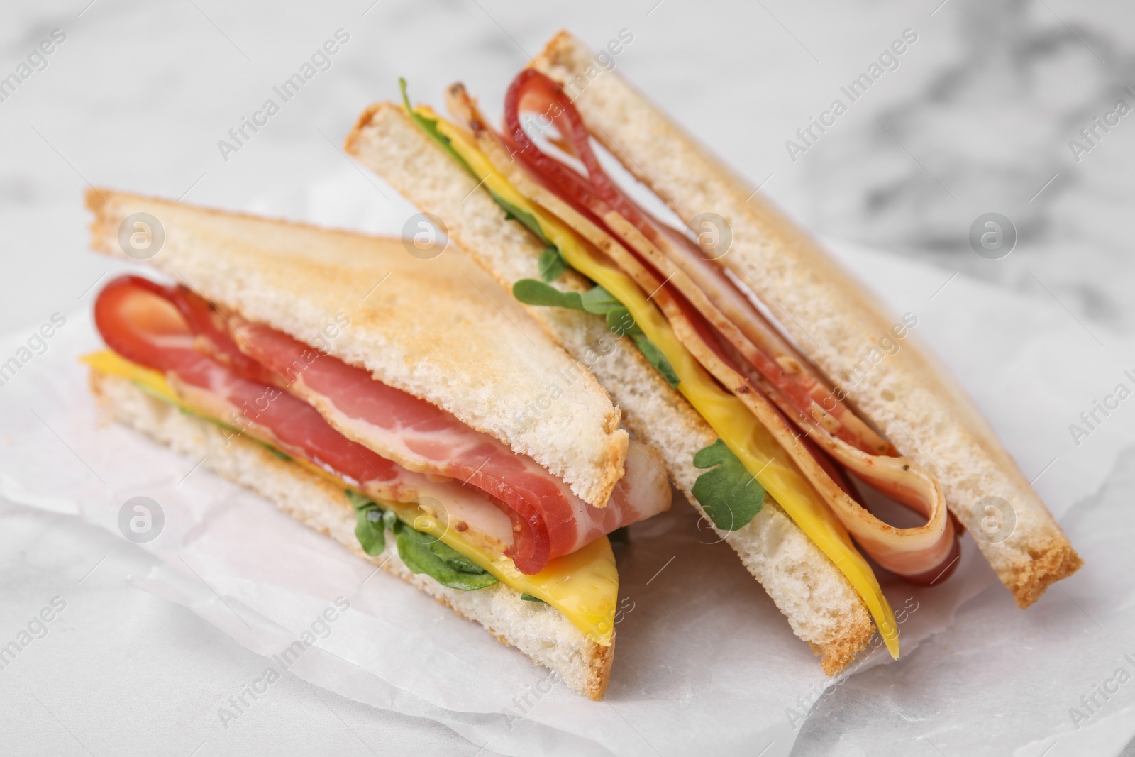 Photo of Delicious sandwiches with bacon on white table, closeup