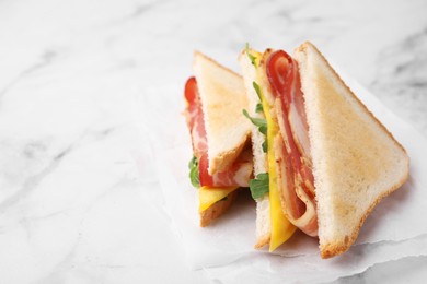 Photo of Delicious sandwiches with bacon on white marble table, closeup. Space for text