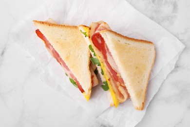 Photo of Delicious sandwiches with bacon on white marble table, top view