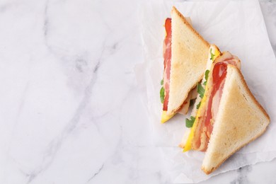 Photo of Delicious sandwiches with bacon on white marble table, top view. Space for text