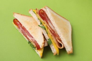 Photo of Delicious sandwiches with bacon on green background, above view