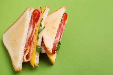 Photo of Delicious sandwiches with bacon on green background, above view. Space for text