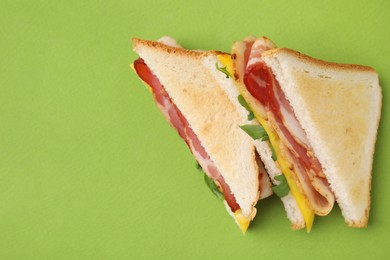 Photo of Delicious sandwiches with bacon on green background, top view. Space for text