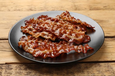 Photo of Slices of tasty fried bacon on wooden table