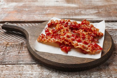 Slices of tasty fried bacon on wooden table