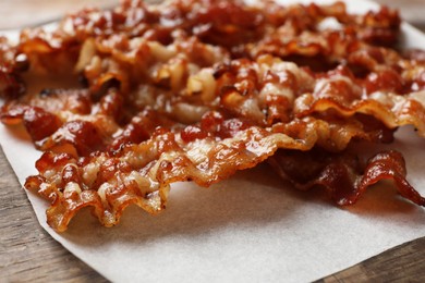 Photo of Slices of tasty fried bacon on wooden table, closeup