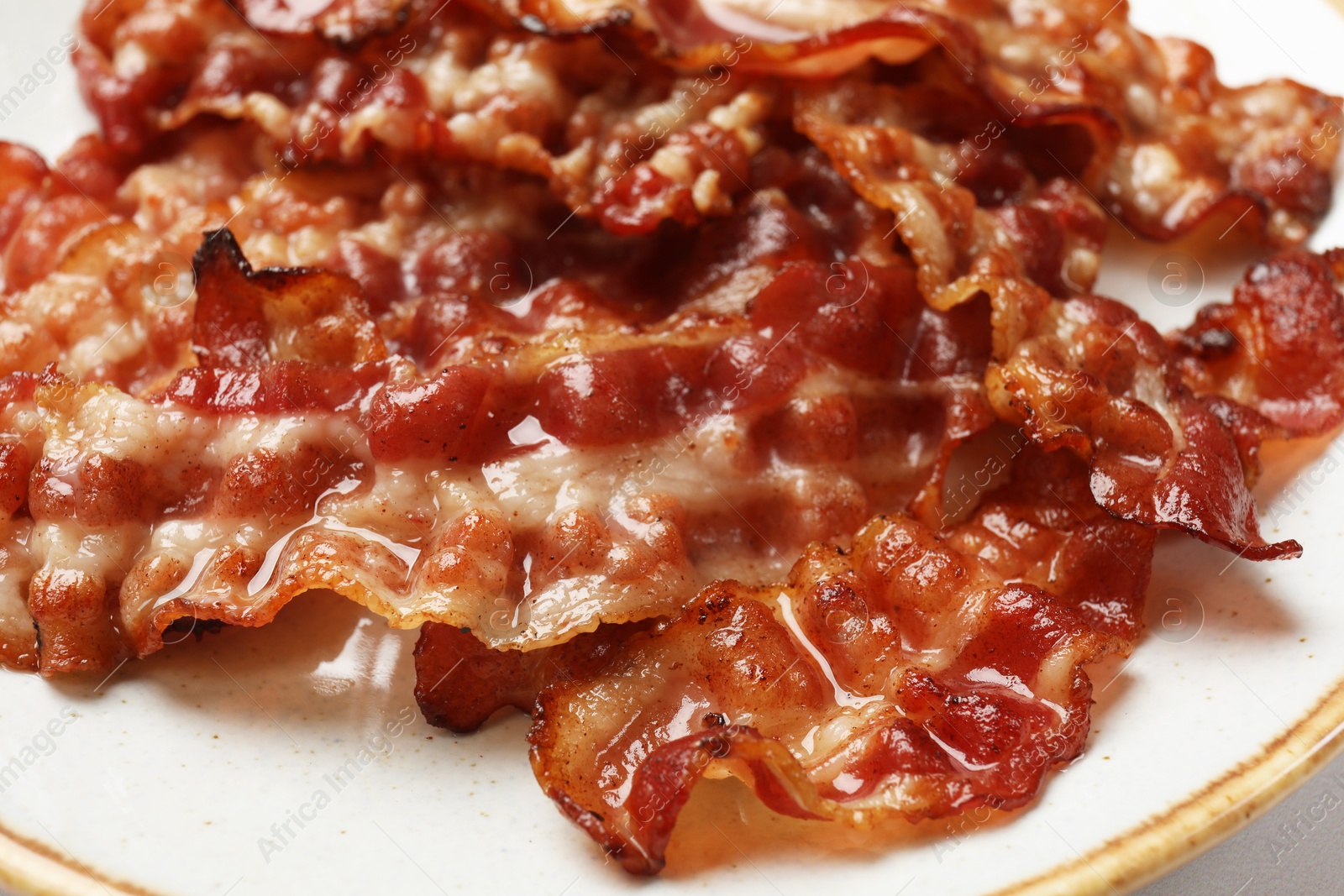 Photo of Slices of tasty fried bacon on table, closeup