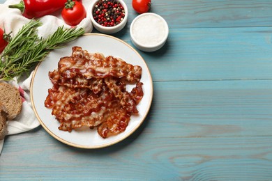 Photo of Slices of tasty fried bacon, different spices and bread on light blue wooden table, top view. Space for text