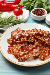 Photo of Slices of tasty fried bacon and different spices on light blue wooden table