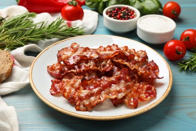 Photo of Slices of tasty fried bacon and different spices on light blue wooden table