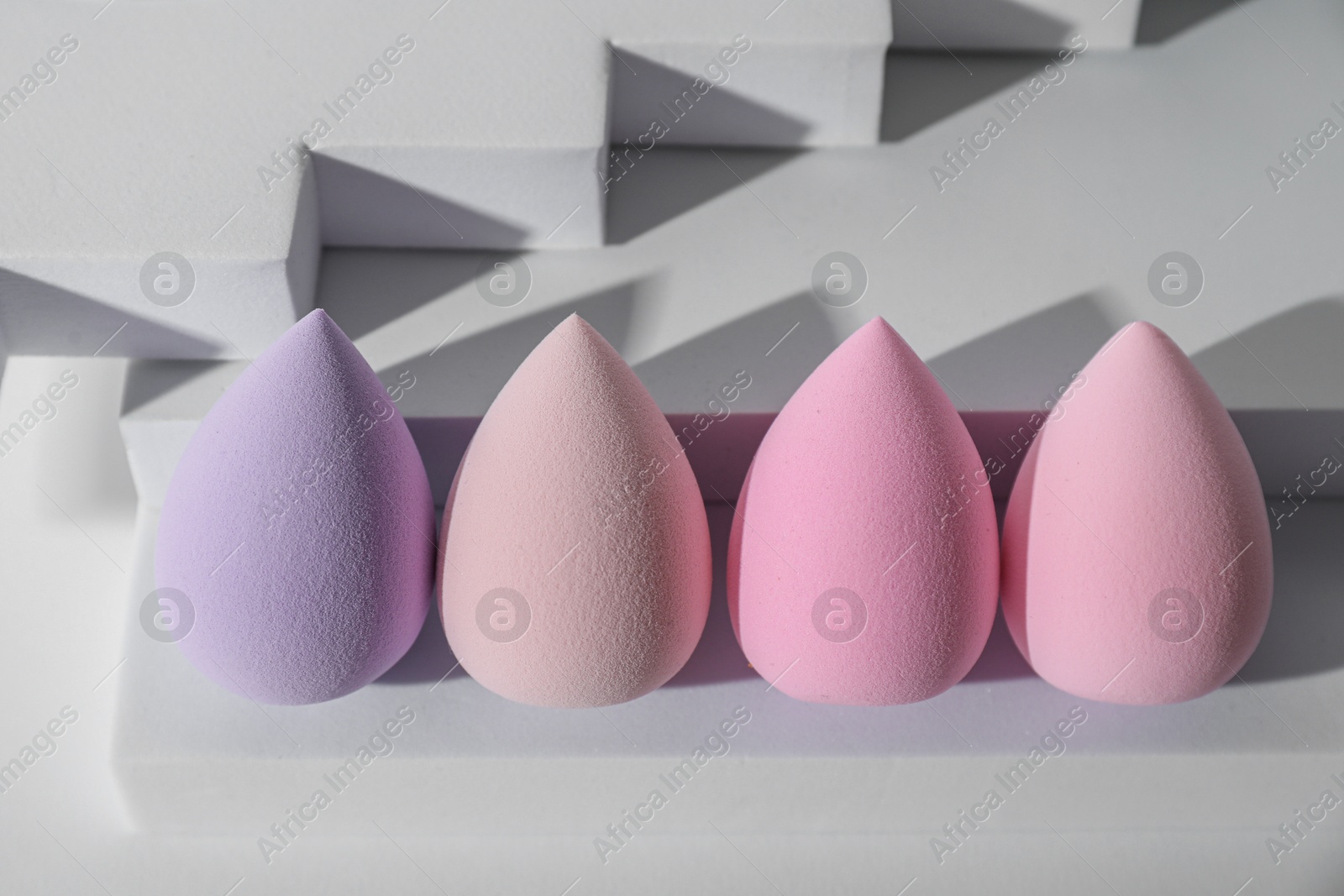 Photo of Stylish presentation of makeup sponges on white background, above view