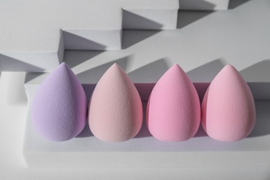 Stylish presentation of makeup sponges on white background, above view