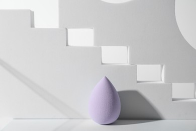 Photo of Stylish presentation of violet makeup sponge on white background