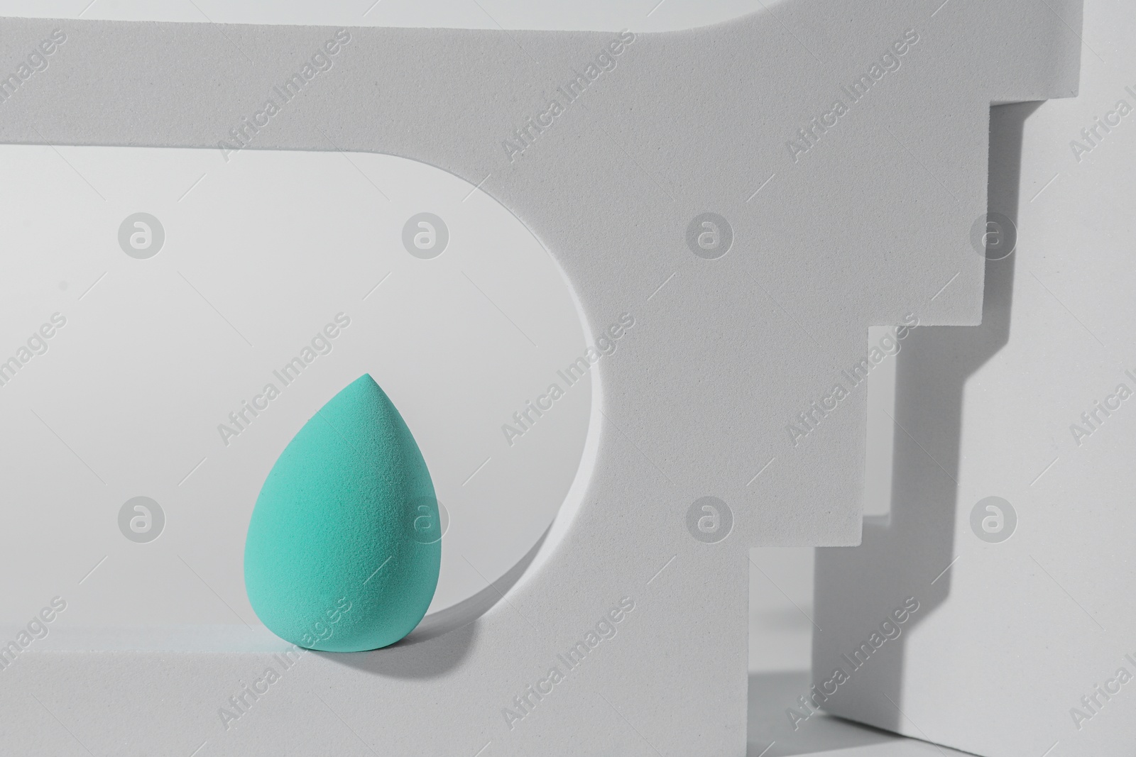 Photo of Stylish presentation of turquoise makeup sponge on white background