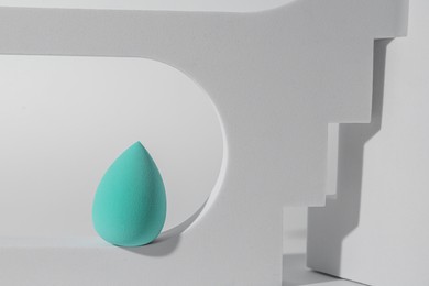 Photo of Stylish presentation of turquoise makeup sponge on white background