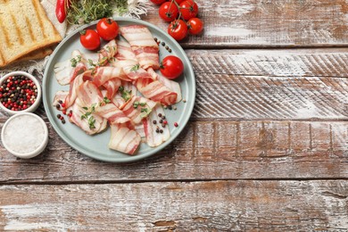 Photo of Slices of raw bacon, spices, bread and tomatoes on wooden table, flat lay. Space for text