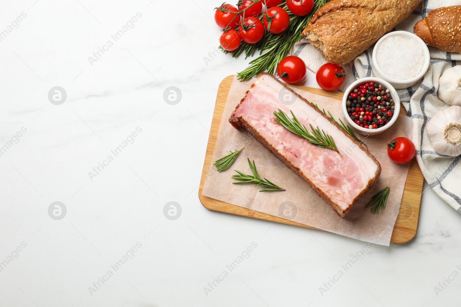 Photo of Piece of raw bacon, spices, bread and tomatoes on white marble table, flat lay. Space for text