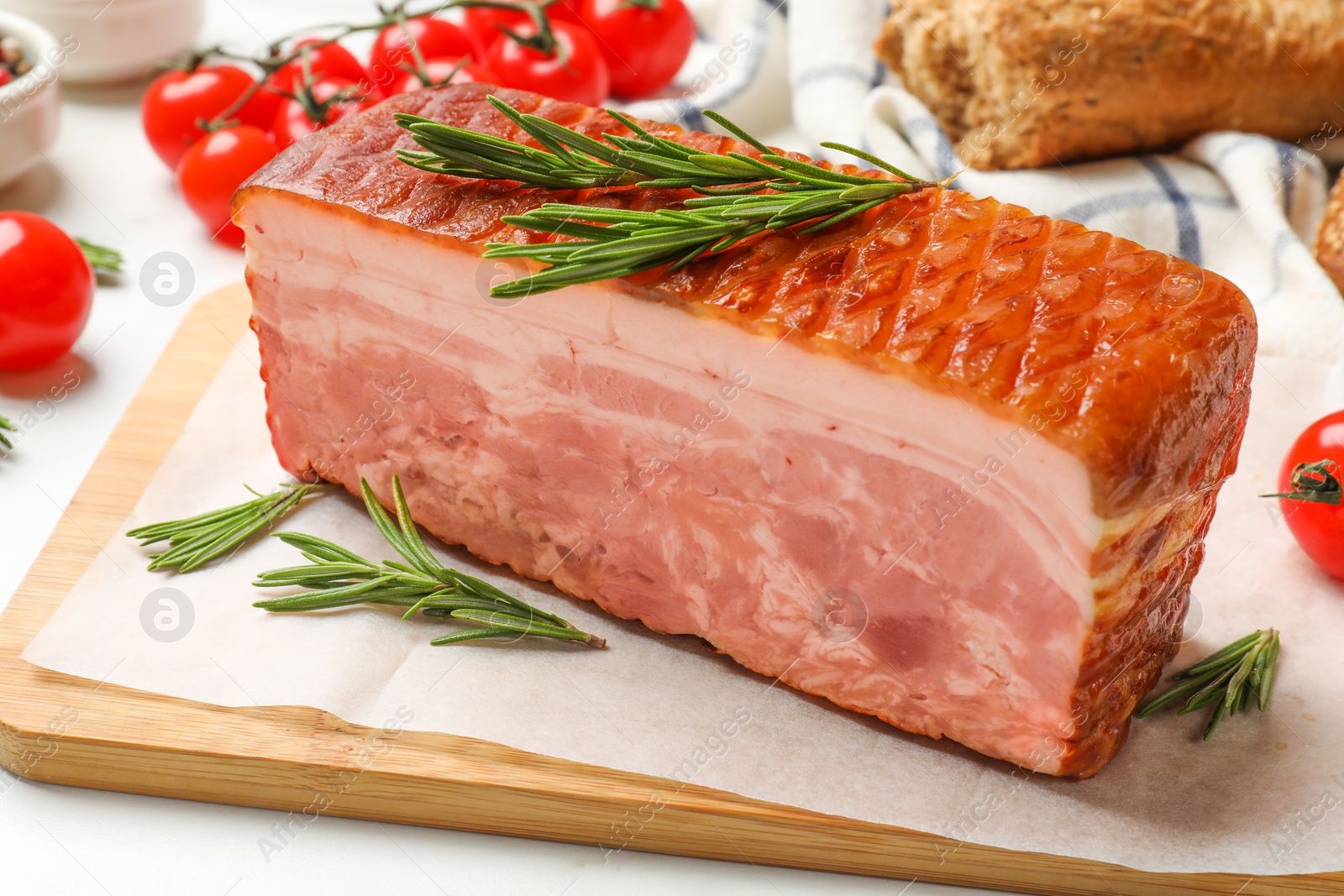 Photo of Piece of raw bacon, rosemary and tomatoes on white table, closeup