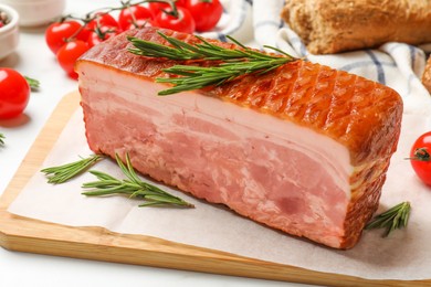 Photo of Piece of raw bacon, rosemary and tomatoes on white table, closeup