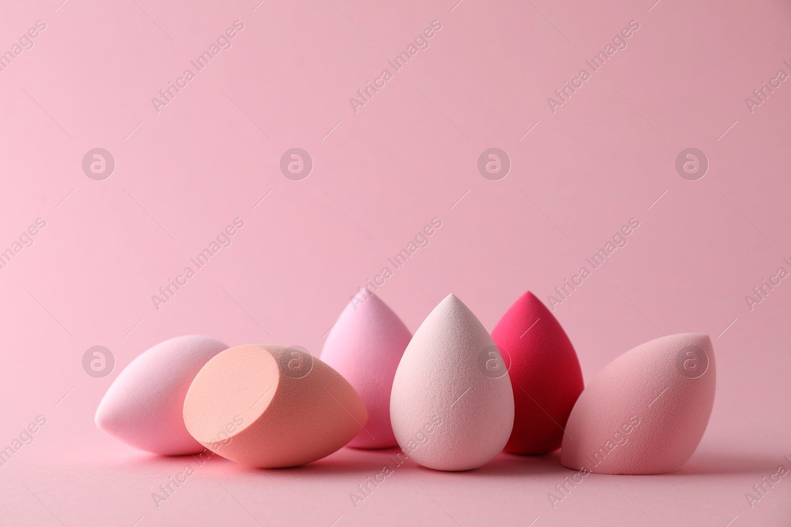 Photo of Many colorful makeup sponges on pink background