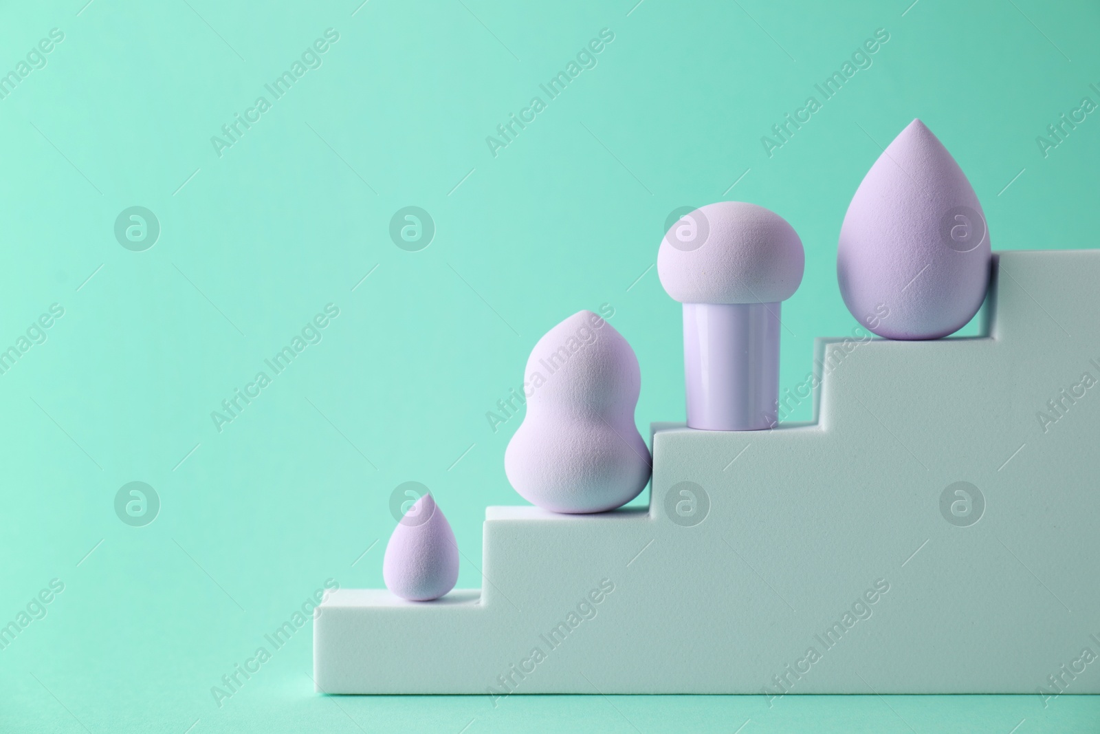 Photo of Stylish presentation of makeup sponges on turquoise background, space for text