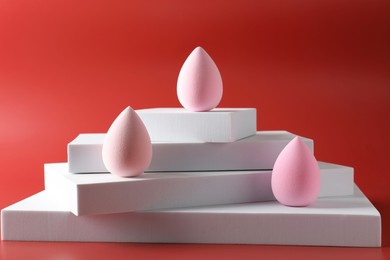 Photo of Stylish presentation of makeup sponges on red background