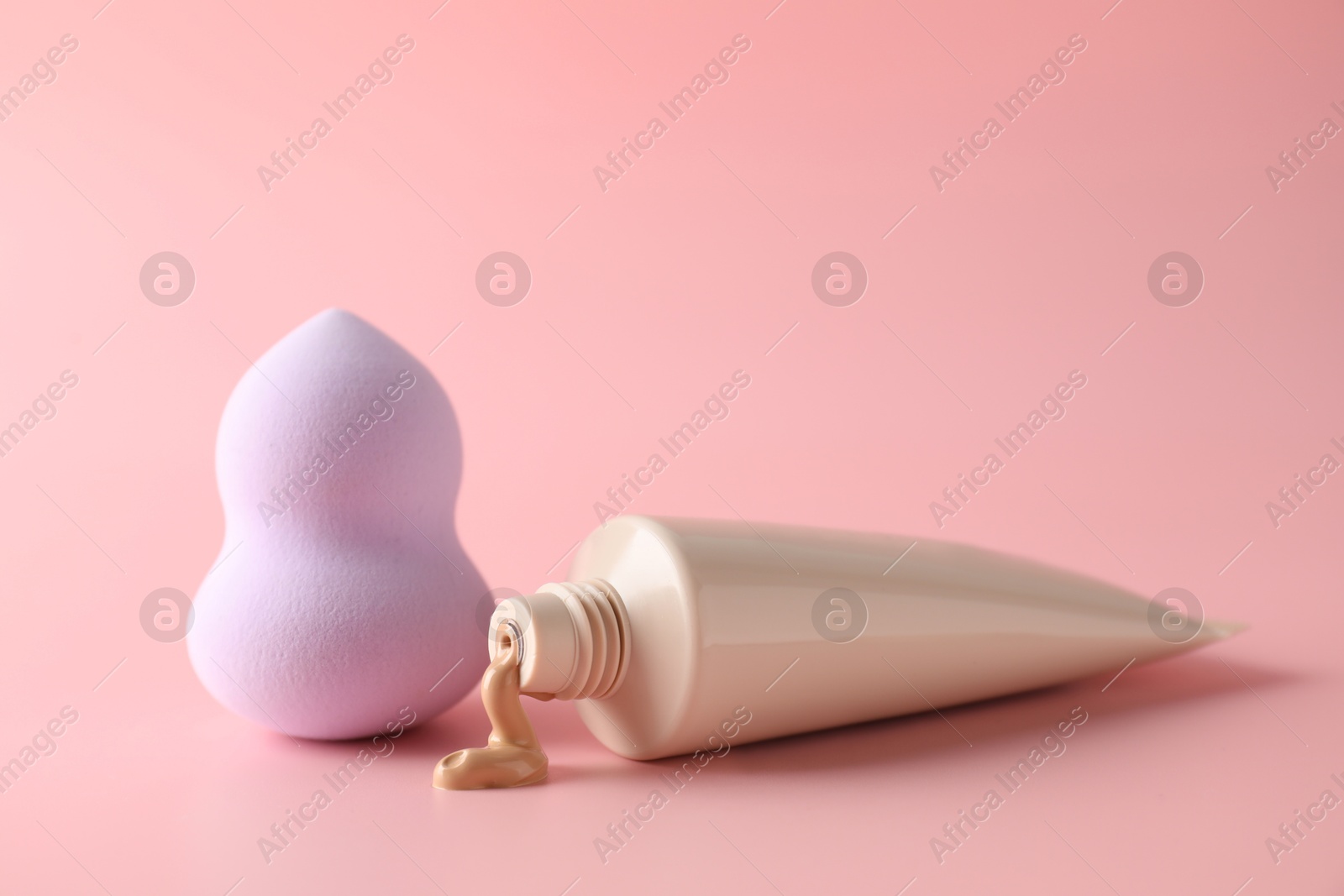 Photo of Makeup sponge and skin foundation on pink background