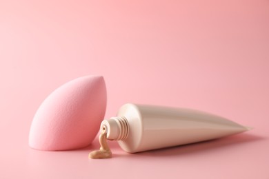 Photo of Makeup sponge and skin foundation on pink background