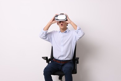 Photo of Emotional young man with virtual reality headset near white wall