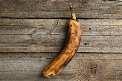 Photo of Overripe banana with dark spots on wooden table, top view