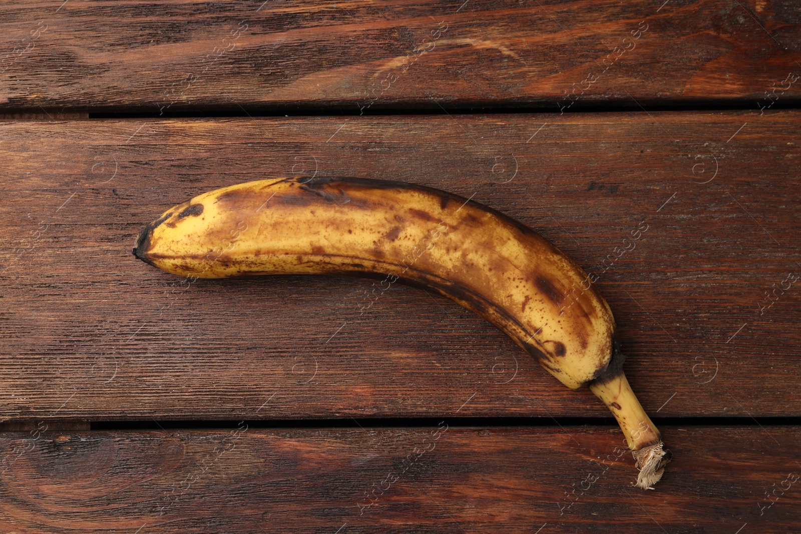 Photo of Overripe banana with dark spots on white wooden table, top view