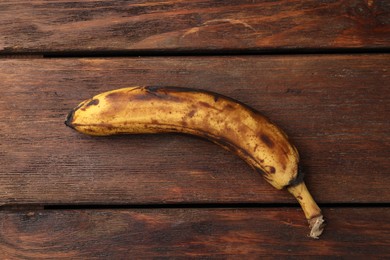 Overripe banana with dark spots on white wooden table, top view