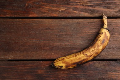 Overripe banana with dark spots on white wooden table, top view. Space for text