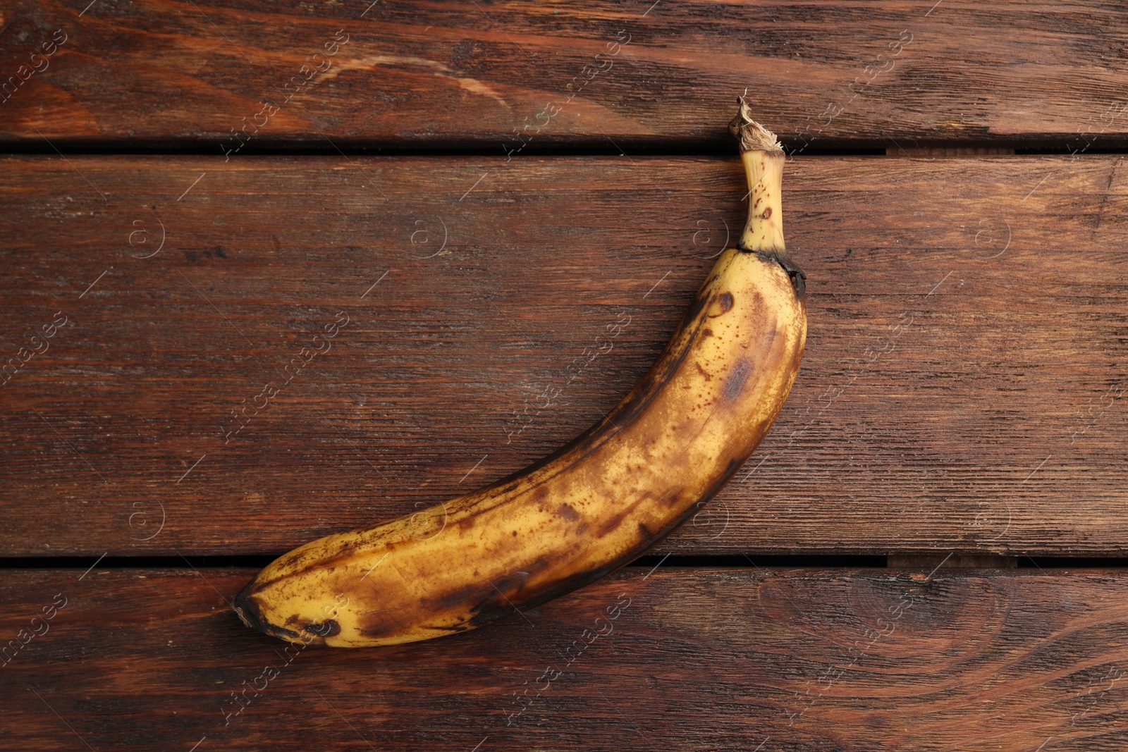 Photo of Overripe banana with dark spots on white wooden table, top view