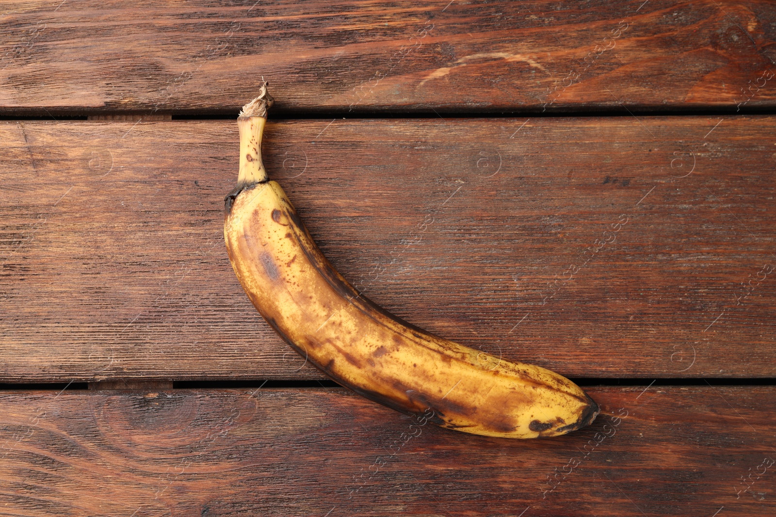 Photo of Overripe banana with dark spots on white wooden table, top view