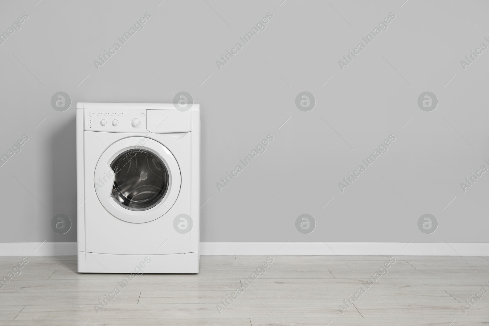 Photo of Washing machine near grey wall indoors, space for text