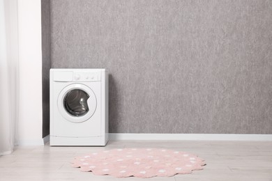 Washing machine near grey wall indoors, space for text