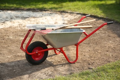 Wheelbarrow with rake and shovel outdoors. Gardening tools