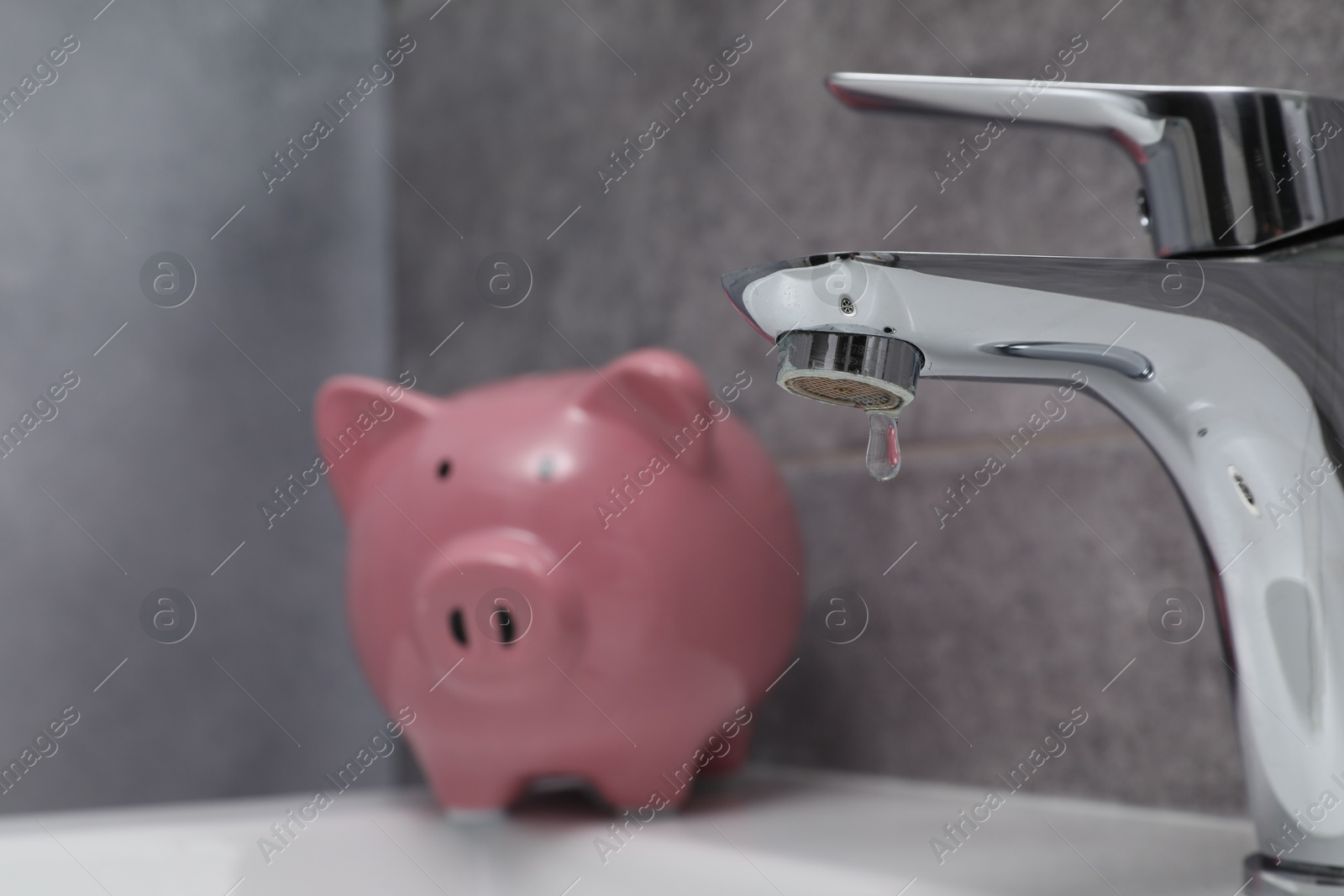 Photo of Water saving concept. Piggy bank and water drop flowing from tap in bathroom, selective focus