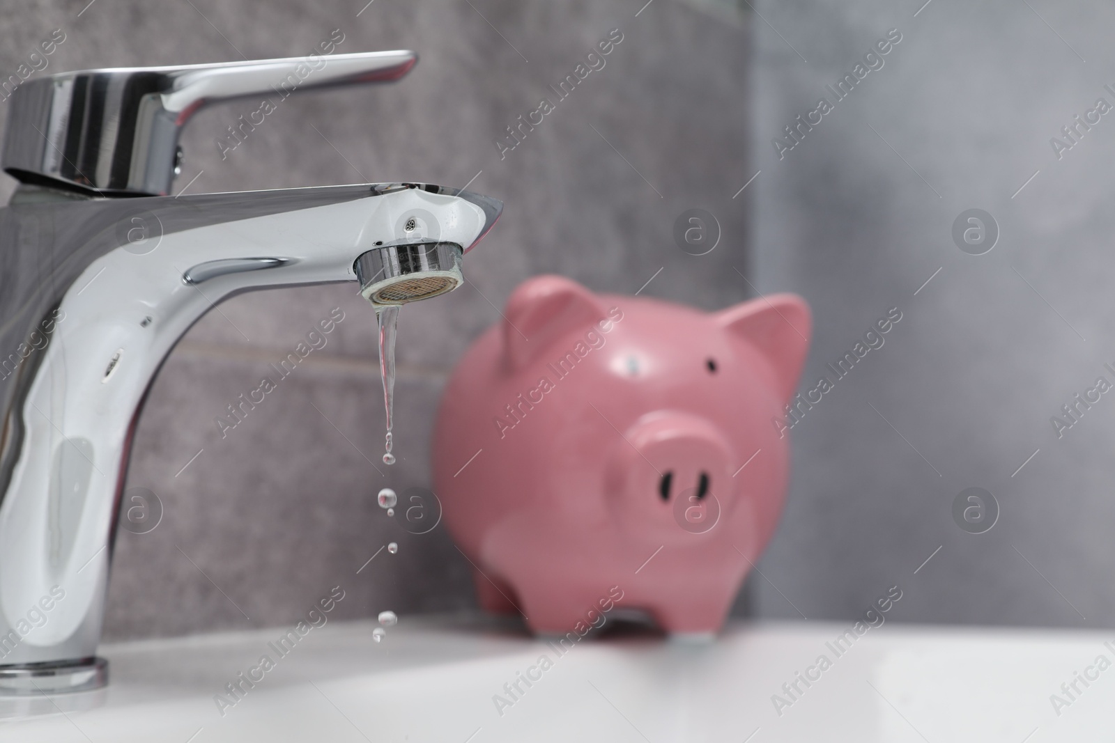 Water saving concept. Piggy bank and water drops flowing from tap in bathroom, selective focus Photo of Water saving concept. Piggy bank and water drops flowing from tap in bathroom, selective focus